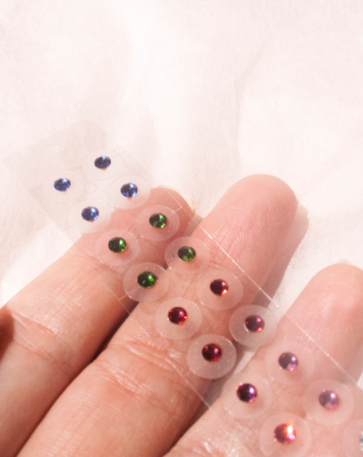 rainbow crystal ear seeds on fingers